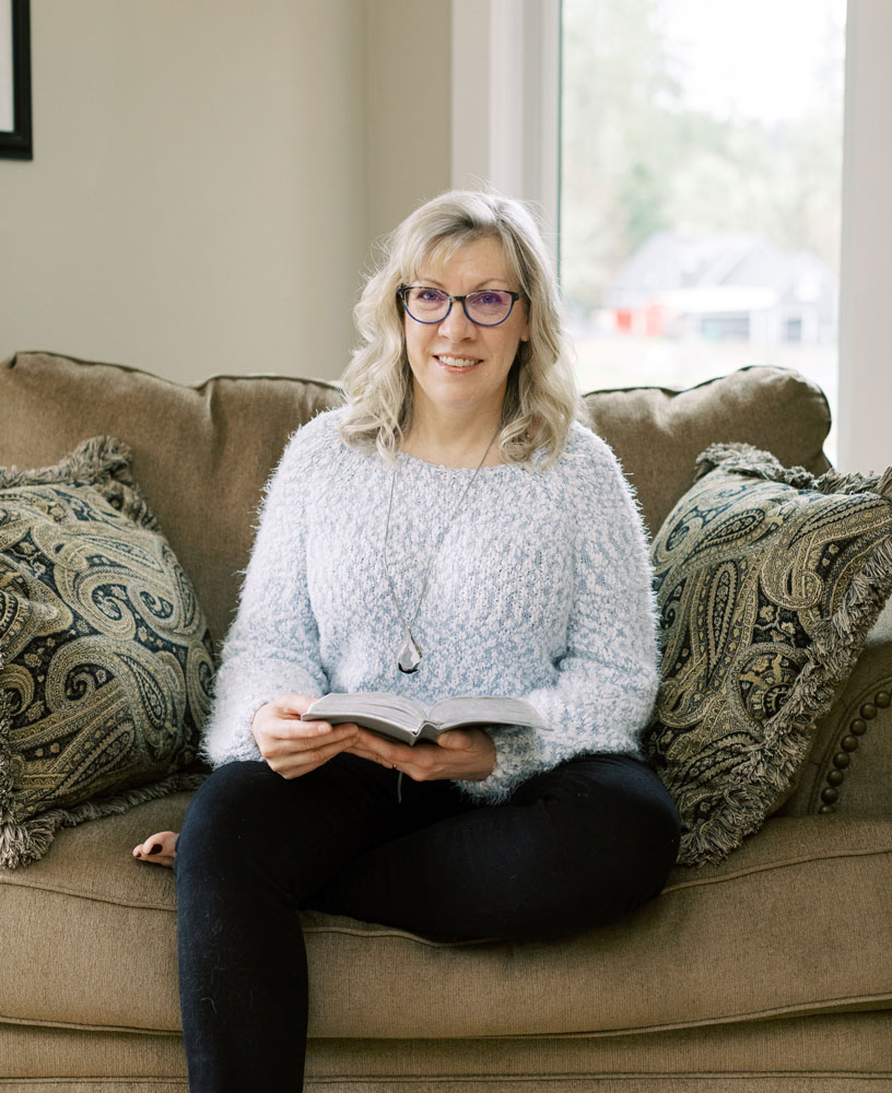 Kendra sitting on comfy chair with Bible in her hands