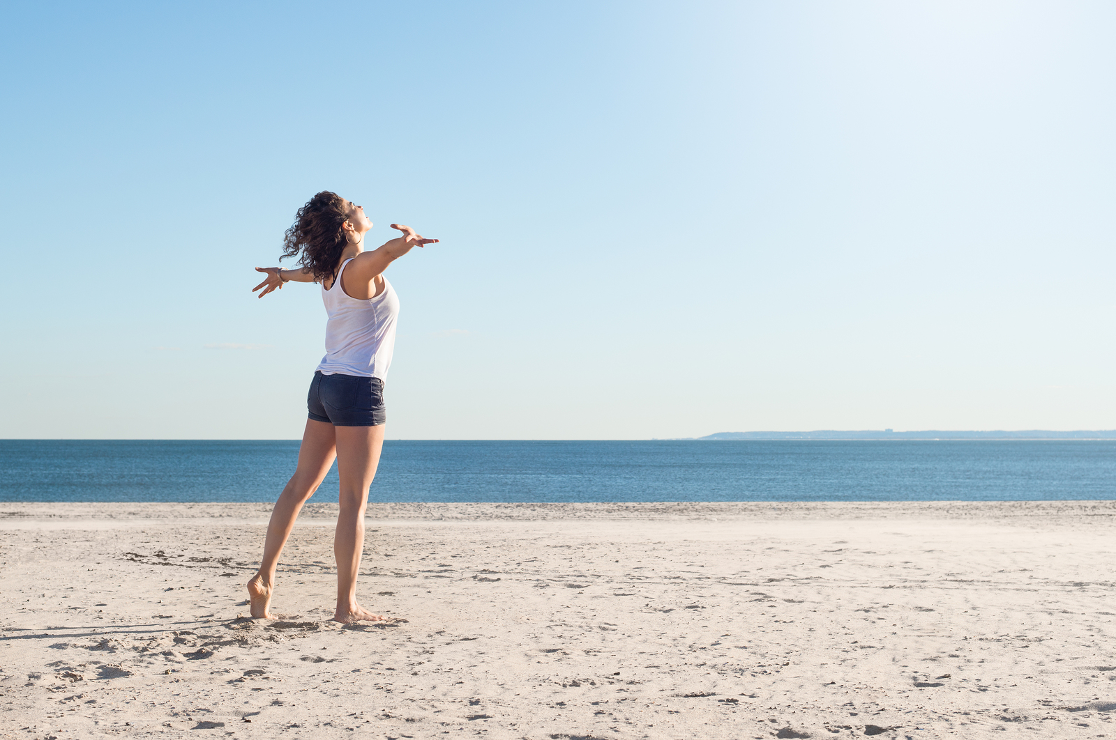 woman on beach with outstretched arms achieving your goals